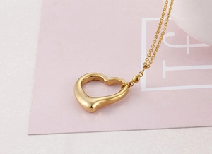 Macro detail of golden open heart pendant with elegant cable chain and small bead