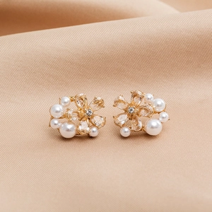 Macro view of gold flower earrings with pearls and crystals on beige silk fabric