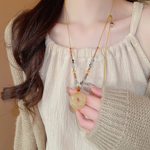 Gros plan d'un collier ethnique en agate avec pendentif en jade porté par un mannequin