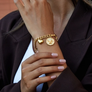 Detail of vintage gold coin bracelet with angel relief and heart charm on wrist