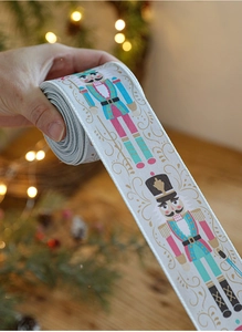 Detail of Christmas ribbon with nutcracker soldier print and festive gold swirls