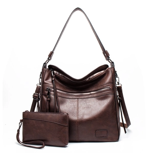 Detail of dark brown pebble leather tote bag with functional zippers and matching clutch bag