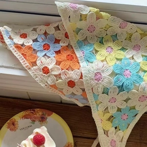 Colorful crochet knit floral triangle headscarf in retro French style on wooden background