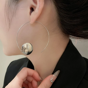 Close-up of minimalist silver hoop earrings with hammered textured discs on a female model