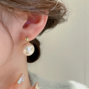 Gros plan sur la boucle d'oreille vintage en perle champagne et son fermoir doré chic