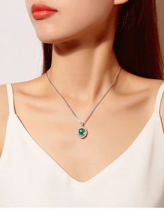 Detail view of a model wearing a S925 silver necklace with green oval gemstone pendant