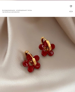Détail de boucles d'oreilles pendantes à fleur rouge foncé vintage sur créoles dorées