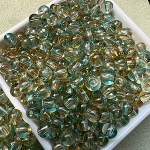 Vue macro de perles en verre rondes dégradé bleu et ambre dans un bol blanc