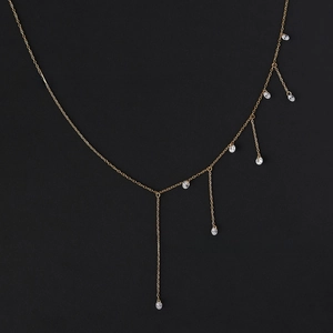 Detailed close-up of golden tassel necklace featuring dangling zircon stone pendants