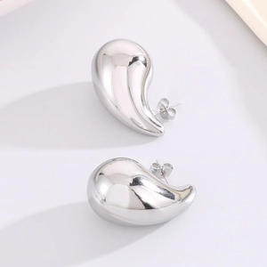 Macro shot of silver teardrop stud earrings with a polished mirror finish surface