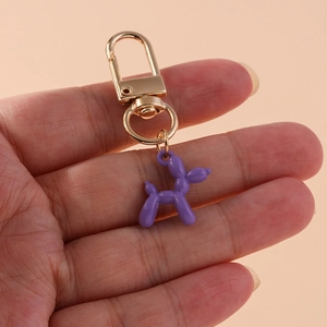 Detail of a purple balloon dog keychain with a polished gold lobster clasp and metal ring