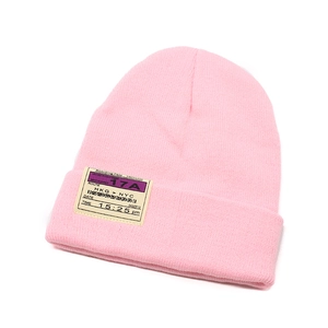 Detail of pink knitted beanie featuring a creative boarding pass theme woven label
