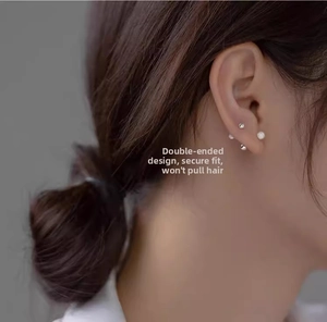Detail showing double-headed metal stud earrings with beads and pearl on a model