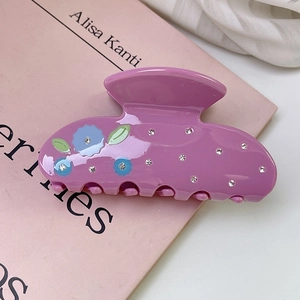 Detail of purple acetate hair claw clip with floral patterns and sparkling rhinestones