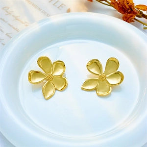 Elegant gold titanium steel flower stud earrings displayed in a minimalist ceramic dish