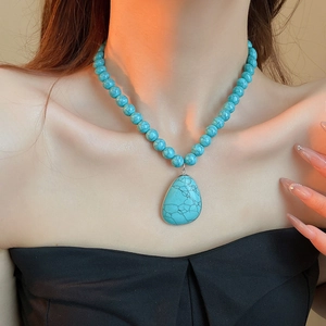 Close-up of bohemian turquoise beaded necklace with a teardrop stone pendant on a model