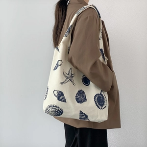 Detail view of large canvas shoulder bag with blue marine print worn by a model