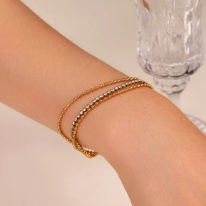 Close-up of layered gold bead and zircon bracelets worn on wrist for a luxury lifestyle look