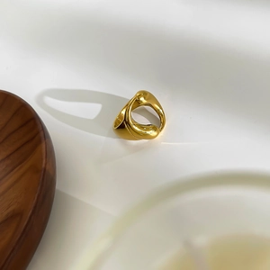 Dettaglio di un anello a goccia dorato con design organico e finitura lucida