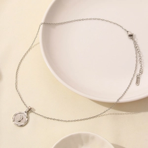 Detailed close-up of a silver stainless steel necklace with a round moon pendant