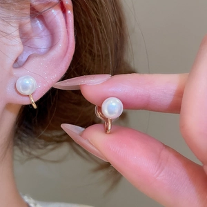 Macro detail of elegant gold-tone pearl ear clip showing secure fit and lustrous texture
