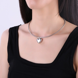 Polished silver heart pendant necklace with snake chain worn on female neck