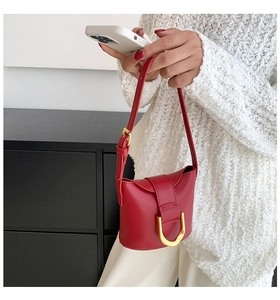 Close-up of red leather crossbody bag with elegant gold horseshoe buckle and strap