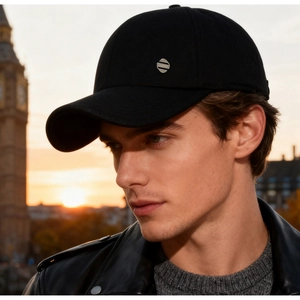 Detail of a black baseball cap featuring a silver metal badge with FASHION engraving