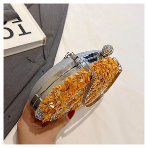 Detail of luxury evening clutch with orange crystals, silver frame and rhinestone closure