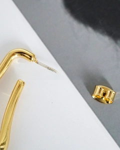 Close-up of golden U-shaped drop earrings showing S925 sterling silver needle stamp