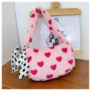 Close-up of pink plush handbag with magenta heart patterns and polka dot silk bow decoration