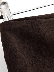 Detailaufnahme der dunkelbraunen Wildleder-Stoffstruktur mit einem Metallclip aus Silber