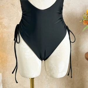 Detail of black high-cut swimsuit featuring side drawstring ruching on a white mannequin