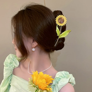 Detail of sunflower hair claw clip with yellow petals on a brunette bun hairstyle