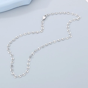 Close-up of silver coffee bean link necklace with lobster clasp on a dual-tone background
