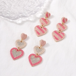 Vintage heart earrings with pearls and rhinestones in pink and gold on linen background