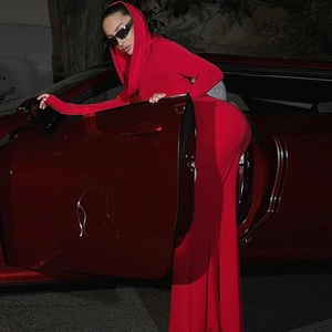 Dettaglio di un abito lungo rosso slim con cappuccio e maniche lunghe accanto a un'auto