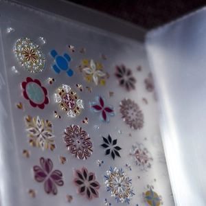 Macro shot of colorful mandala flower nail stickers in a clear storage pocket binder