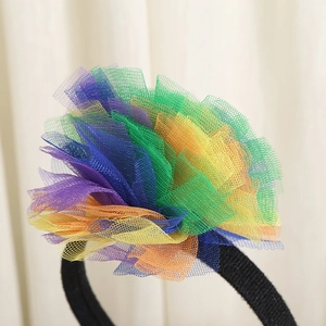 Detailed close-up of colorful rainbow mesh flower on a black headband bohemian style