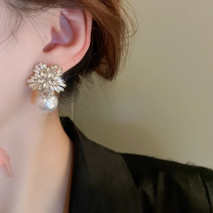 Close-up of floral zirconia earring with a white pearl pendant worn by a model
