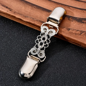 Macro detail of silver filigree cardigan clip with sparkling rhinestones on black background