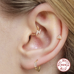 Macro-opname van vergulde 925 sterling zilveren bliksem en geometrische piercings