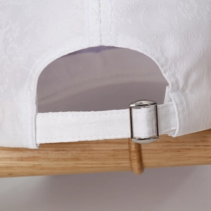 Detail of white jacquard baseball cap with adjustable metal buckle and textured fabric
