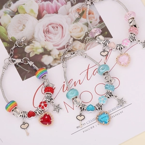 Three DIY charm bracelets with heart crystals and starfish charms on pink floral background