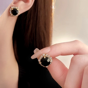 Detail of vintage gold stud earrings with black gemstone and sparkling crystal halo