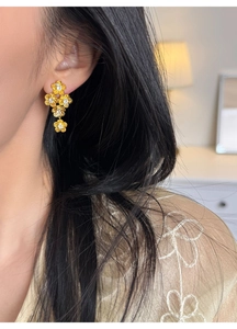 Macro shot of tiered golden flower drop earrings with sparkling central zircon stones