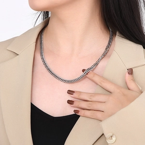 Collier à maille gourmette argentée en acier inoxydable porté par un mannequin en veste