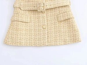 Close-up of textured tweed fabric showing metallic threads and gold-tone button detail