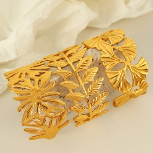 Gold titanium steel leaf bangles with hollow ginkgo patterns on a beige stone base
