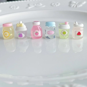 Close-up of miniature resin juice bottles with fruit patterns for DIY crafts and decor